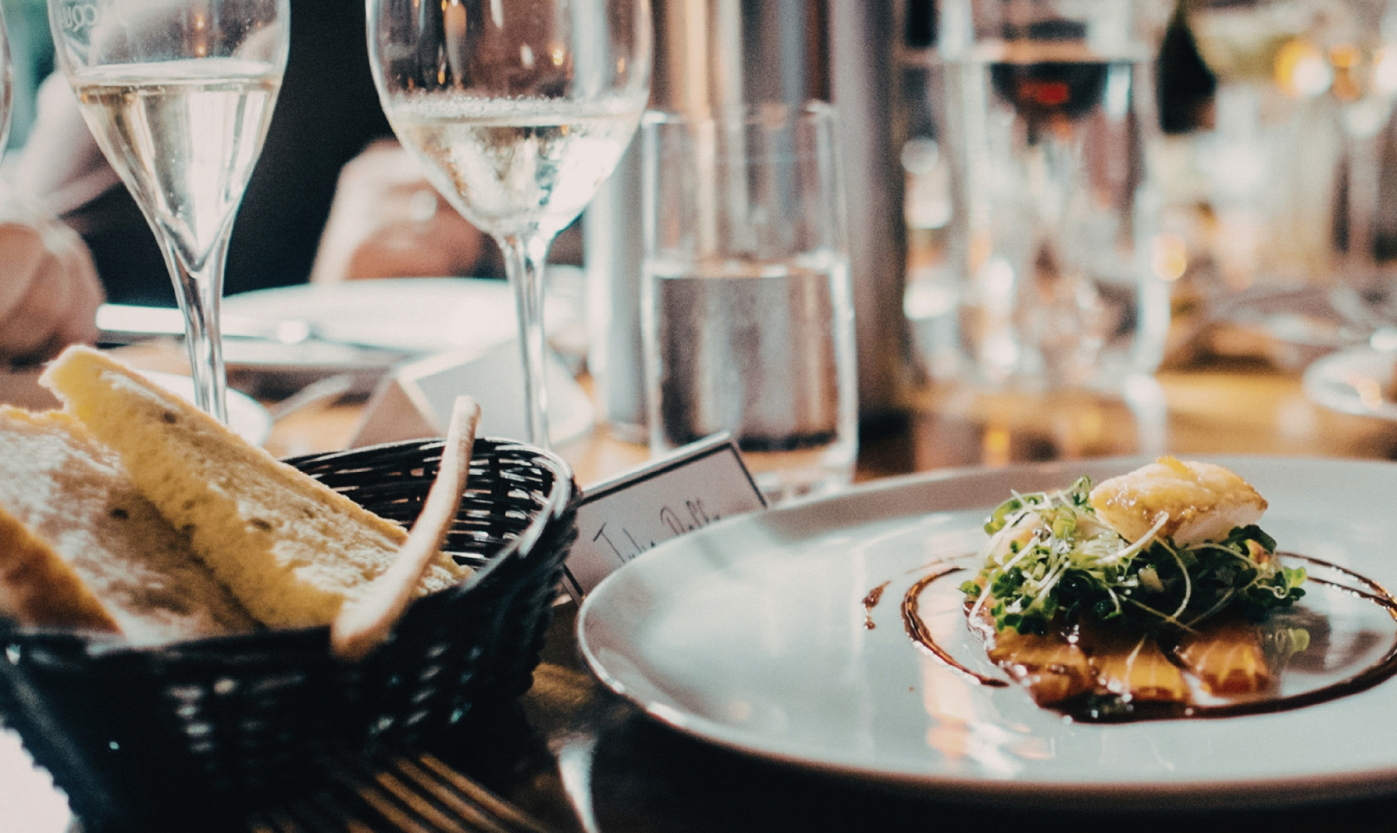 fine dining table setting with composed entree on plate, clear wine glasses and water glasses