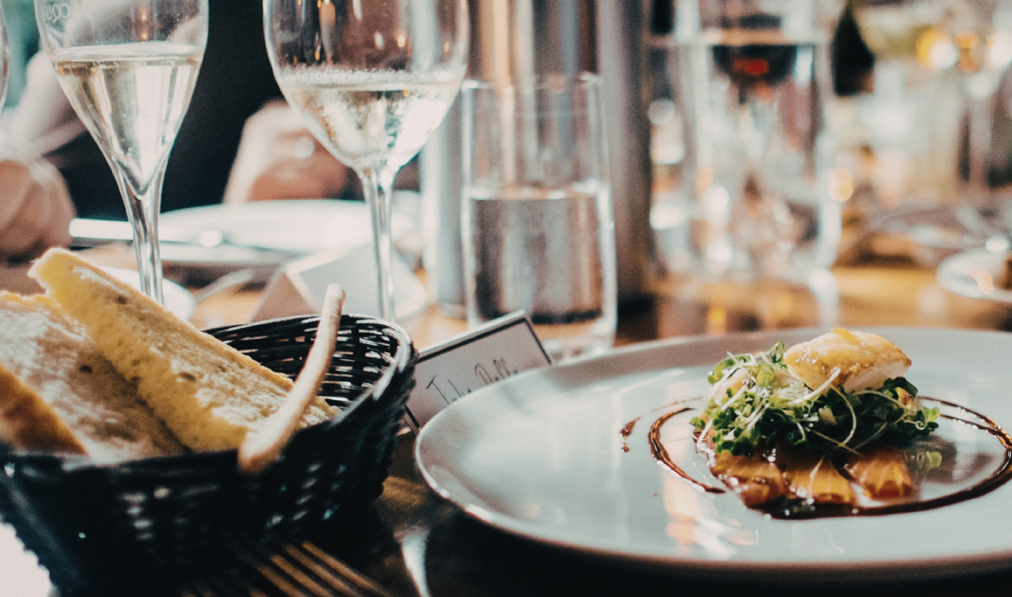 fine dining table setting with composed entree on plate, clear wine glasses and water glasses