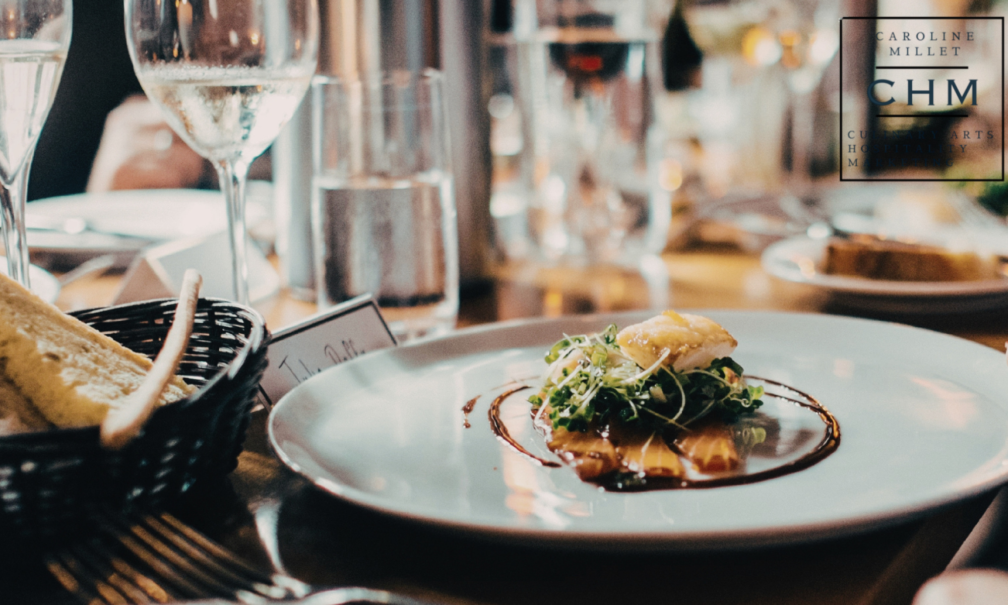 fine dining table setting with composed entree on plate, clear wine glasses and water glasses
